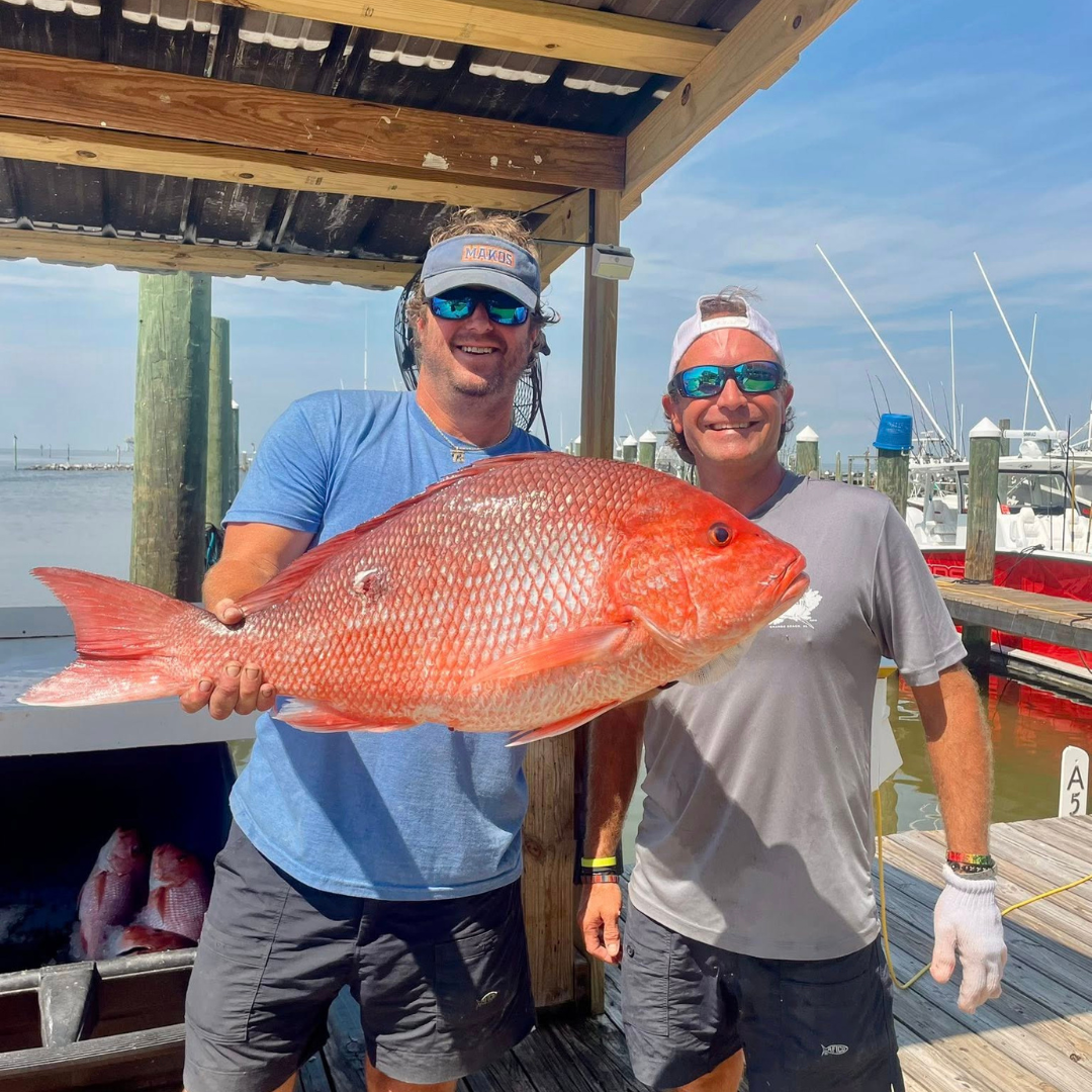 captain and first mate with large red snapper after offshore fishing charter on the gulf