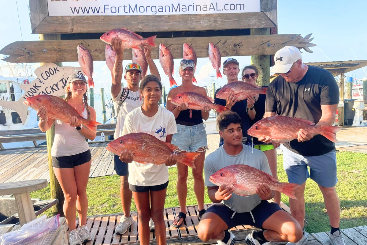 family group at fort morgan marina taking pictures with their catch of red snapper after offshore fishing trip