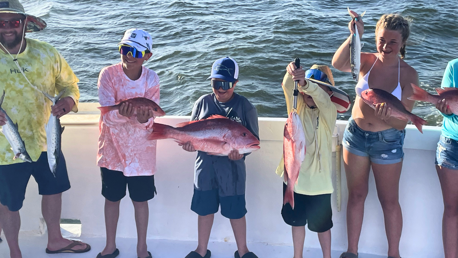 family group on back deck of no doubt charter boat holding red snapper caught out of Fort Morgan