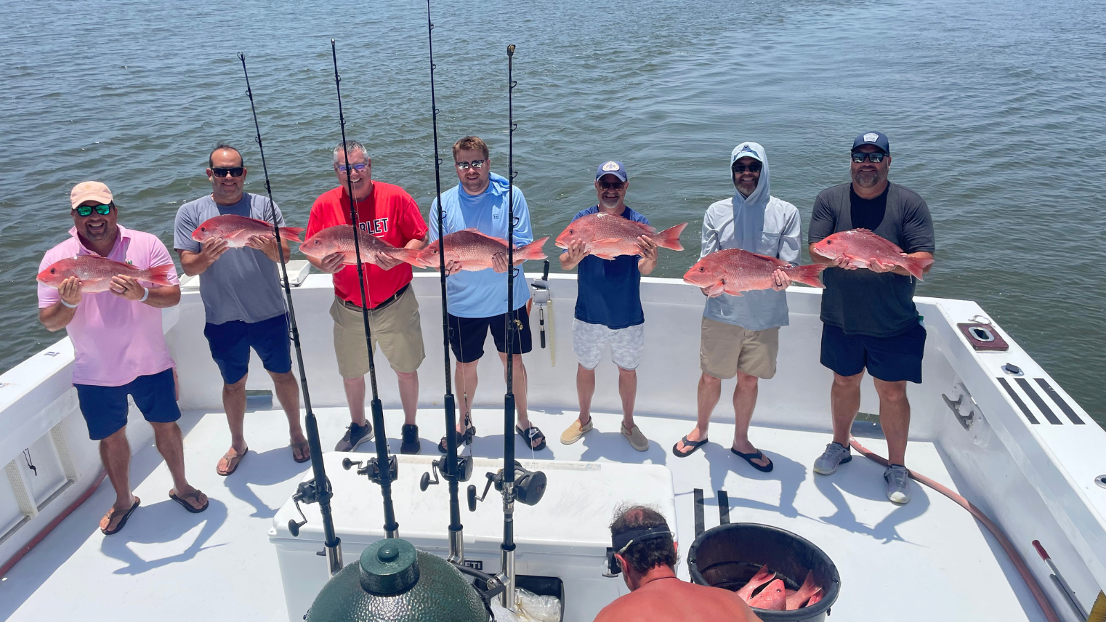 group of guys aboard charter fishing trip offshore with red snapper catch