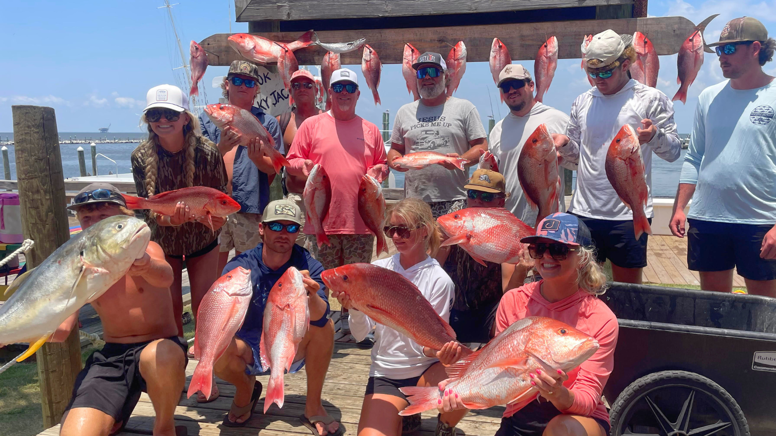large group showing off catch of red snapper caught on offshore fishing trip back at the dock at fort morgan marina