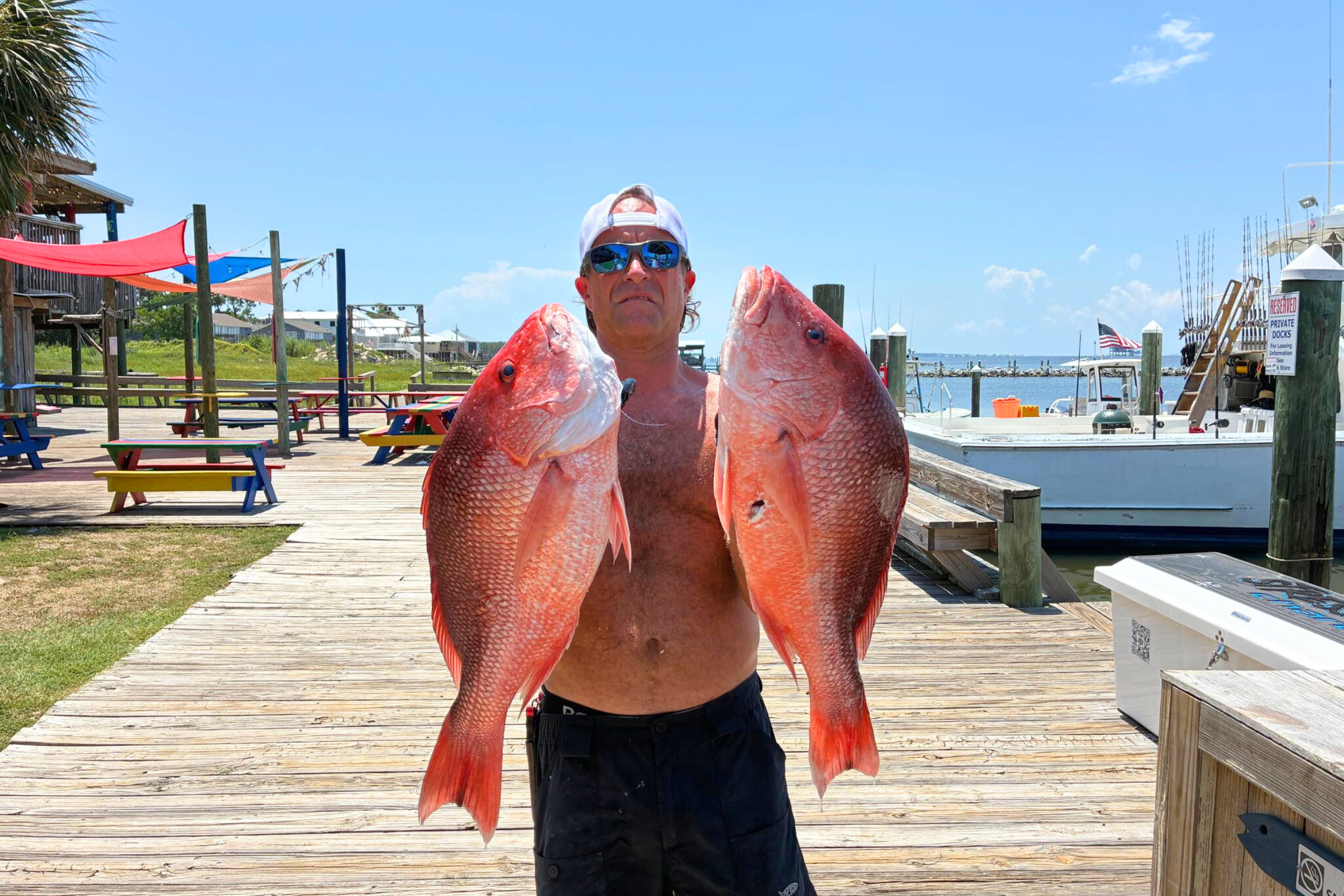 first mate brannon house holding up two large red snapper caught on offshore fishing charter out of fort morgan